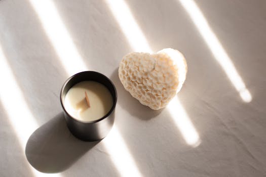 A serene tableau of a textured heart candle beside a luxury soy candle on a sunlit surface.