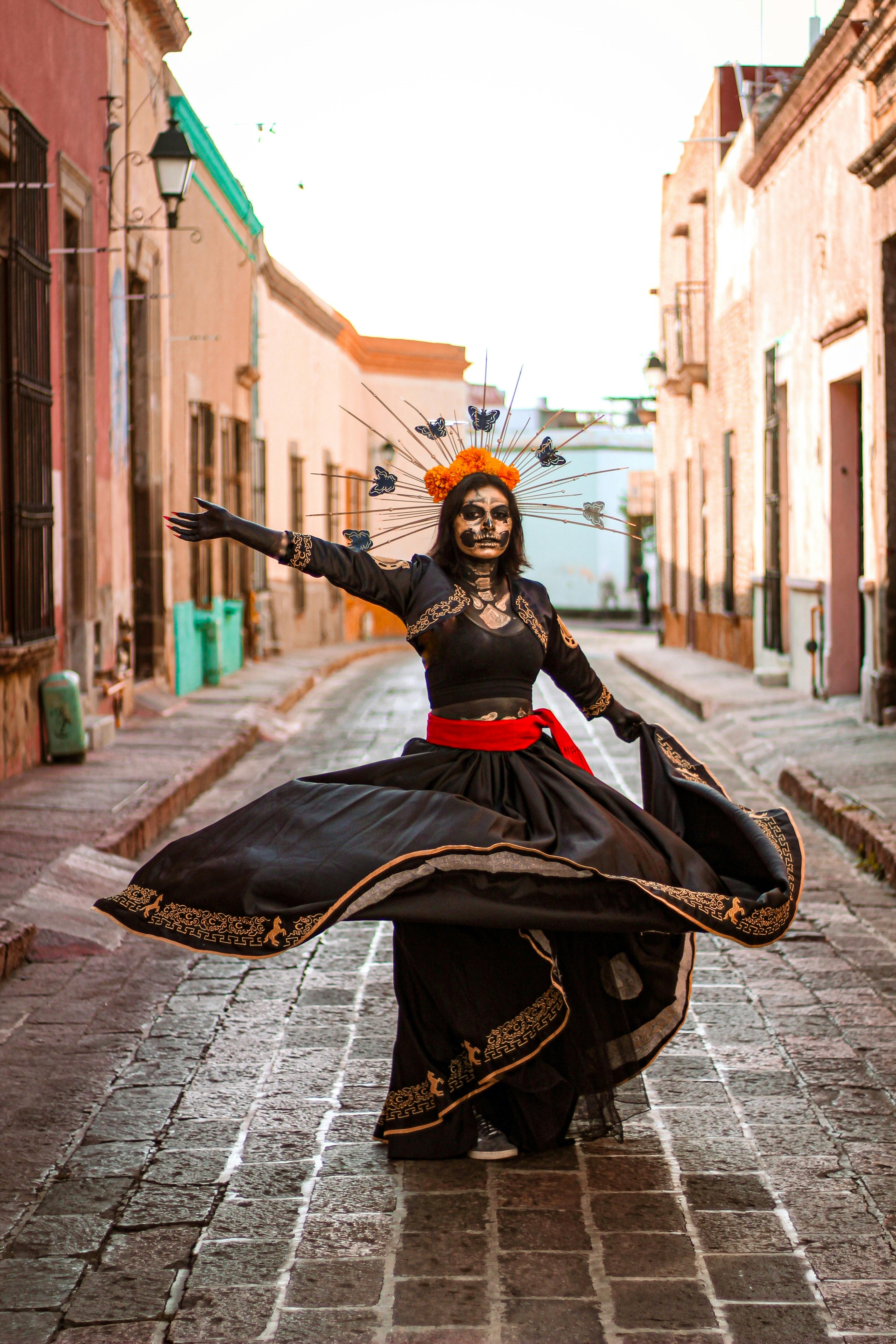 a woman dressed as a catrina dancing on a street