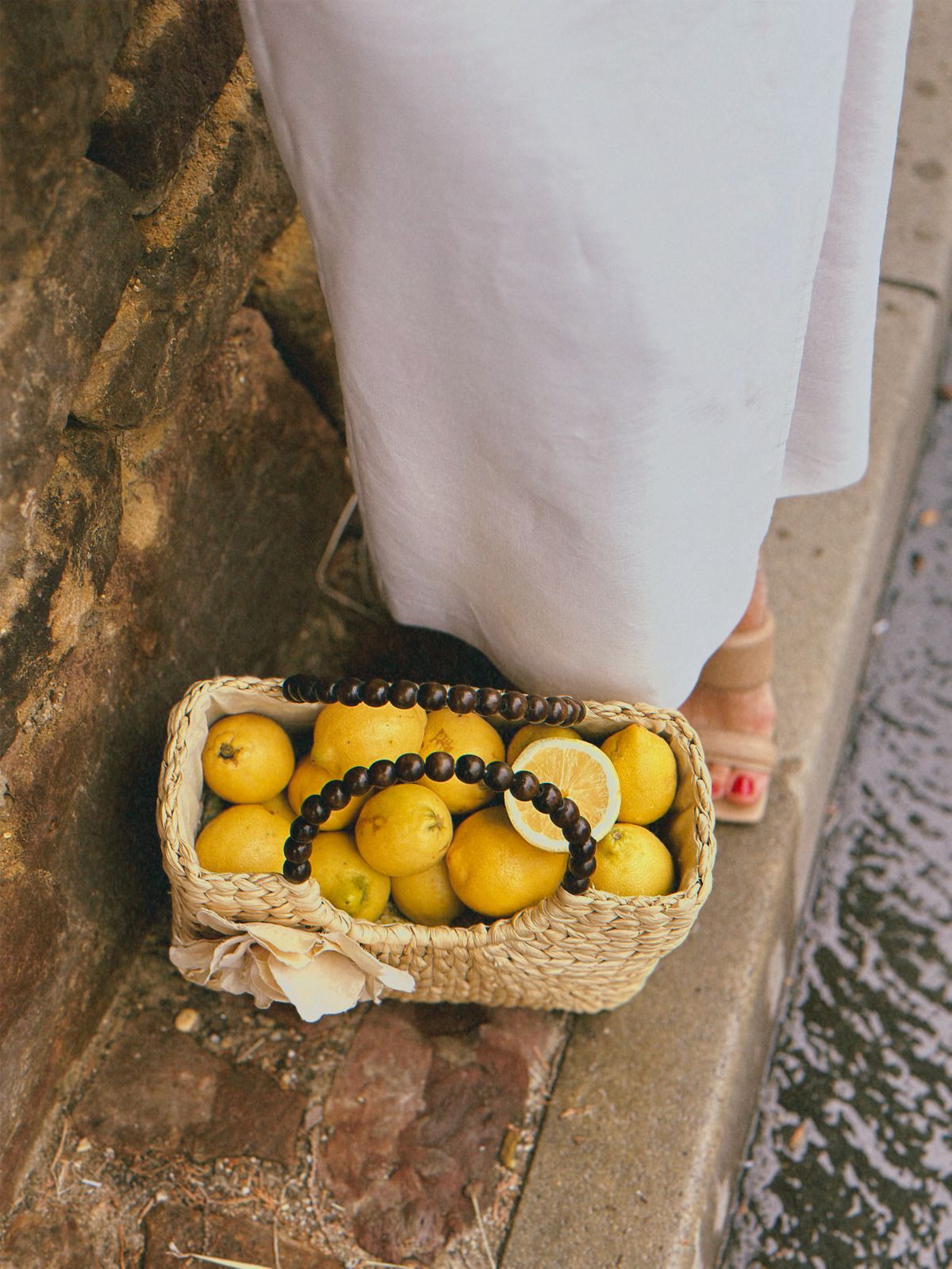 Straw purse filled with lemons on a narrow pavement