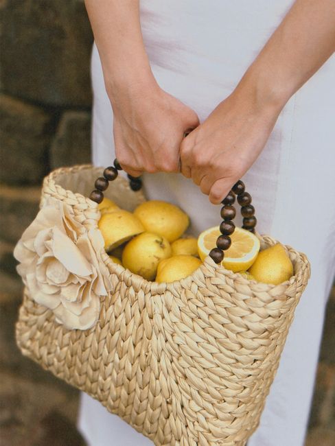 A woman holding a woven basket full of fresh lemons, highlighting a natural lifestyle.