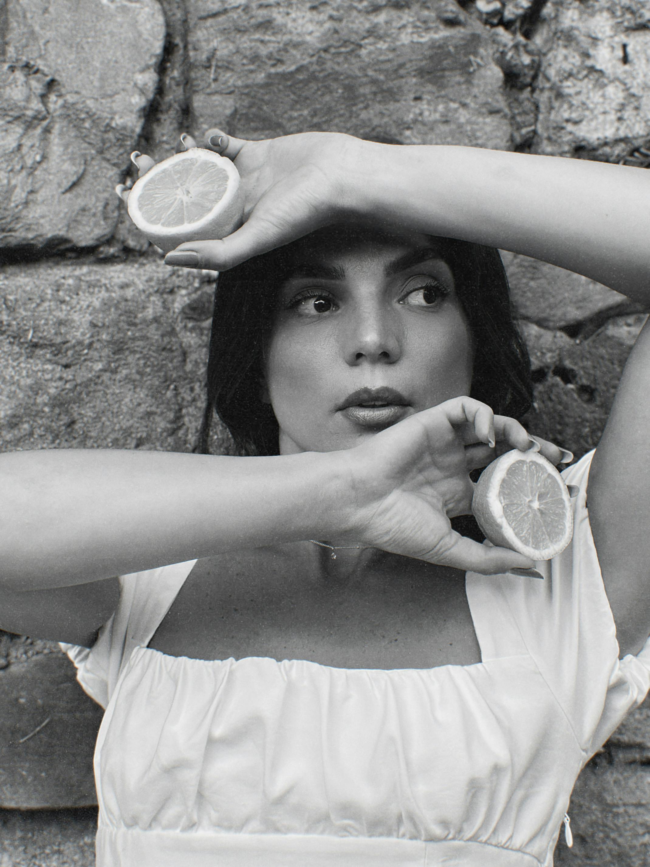 Styled portrait of a woman holding lemons in black and white.
