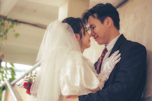 Bride and groom embrace lovingly at their wedding, showcasing elegant fashion and joyous celebration.