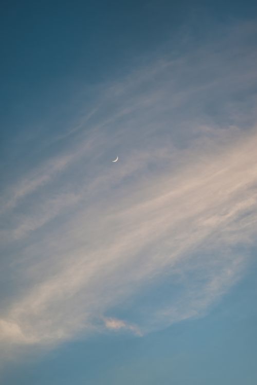 Free A tranquil sky featuring a thin crescent moon amidst wispy clouds, perfect for mobile wallpaper. Stock Photo
