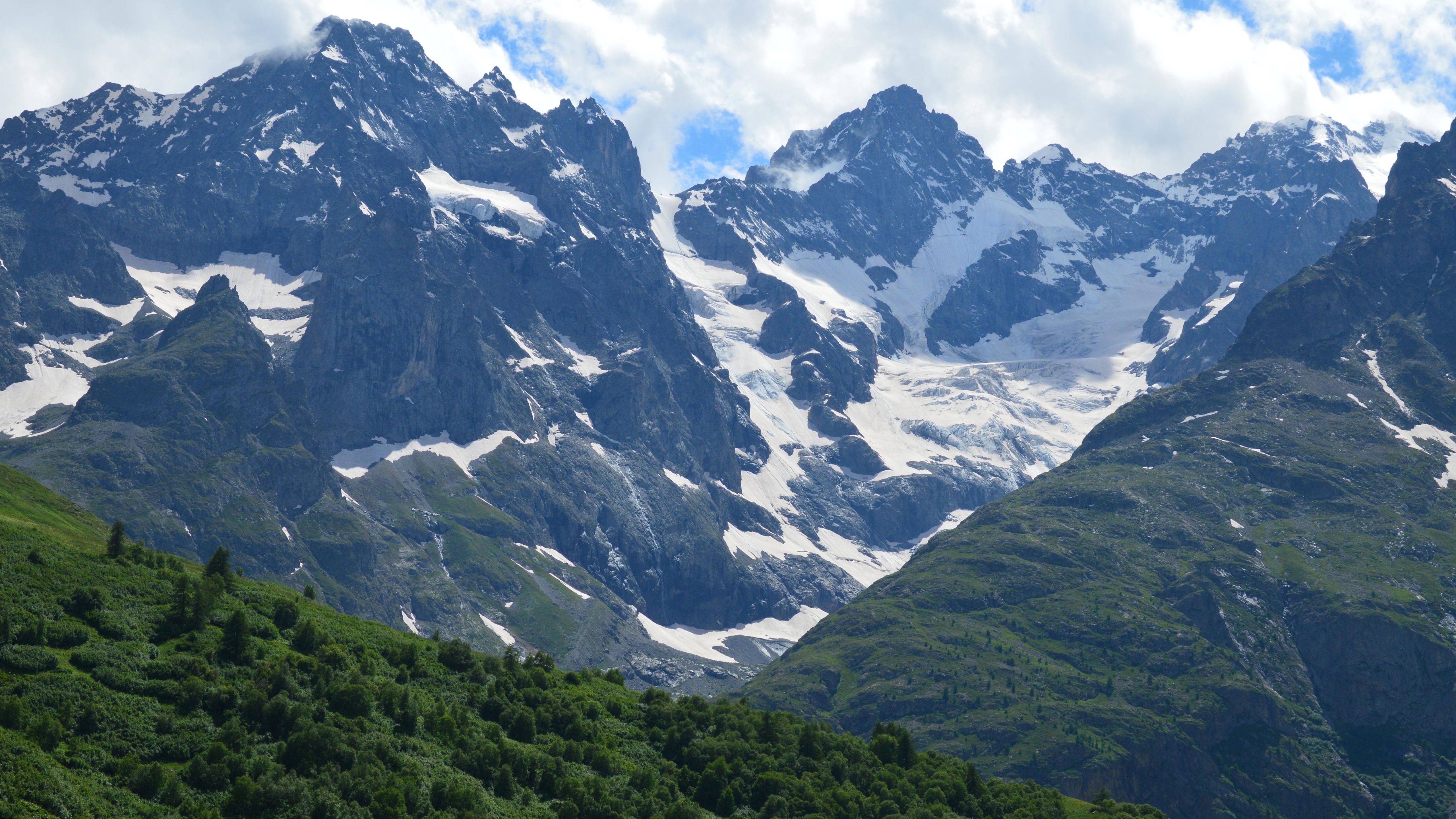 A mountain range with snow covered peaks and green grass · Free Stock Photo