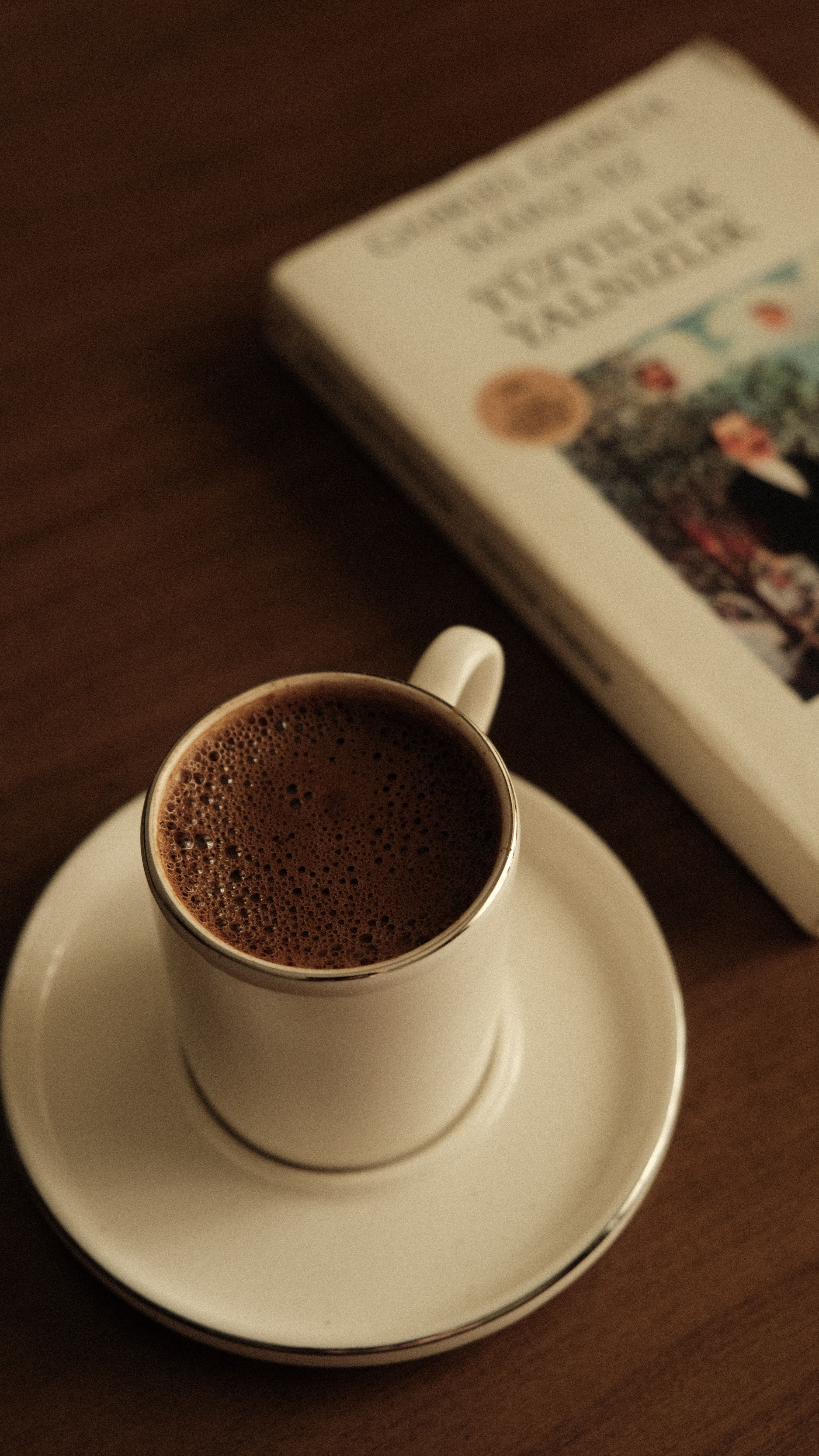 A warm cup of black coffee beside a classic novel on a wooden table, creating a relaxing ambiance.