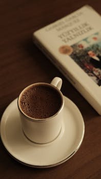 A warm cup of black coffee beside a classic novel on a wooden table, creating a relaxing ambiance.