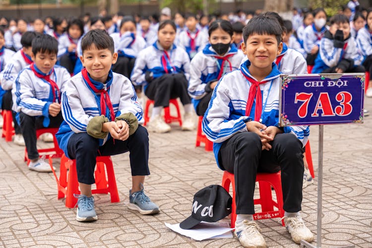 Schoolkids Sitting On The Chairs Outside 