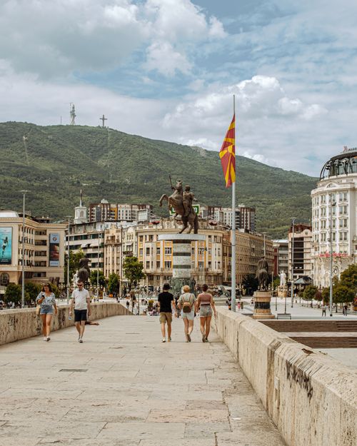Free A vibrant cityscape of Skopje with the historic Stone Bridge and Macedonian flag waving. Stock Photo