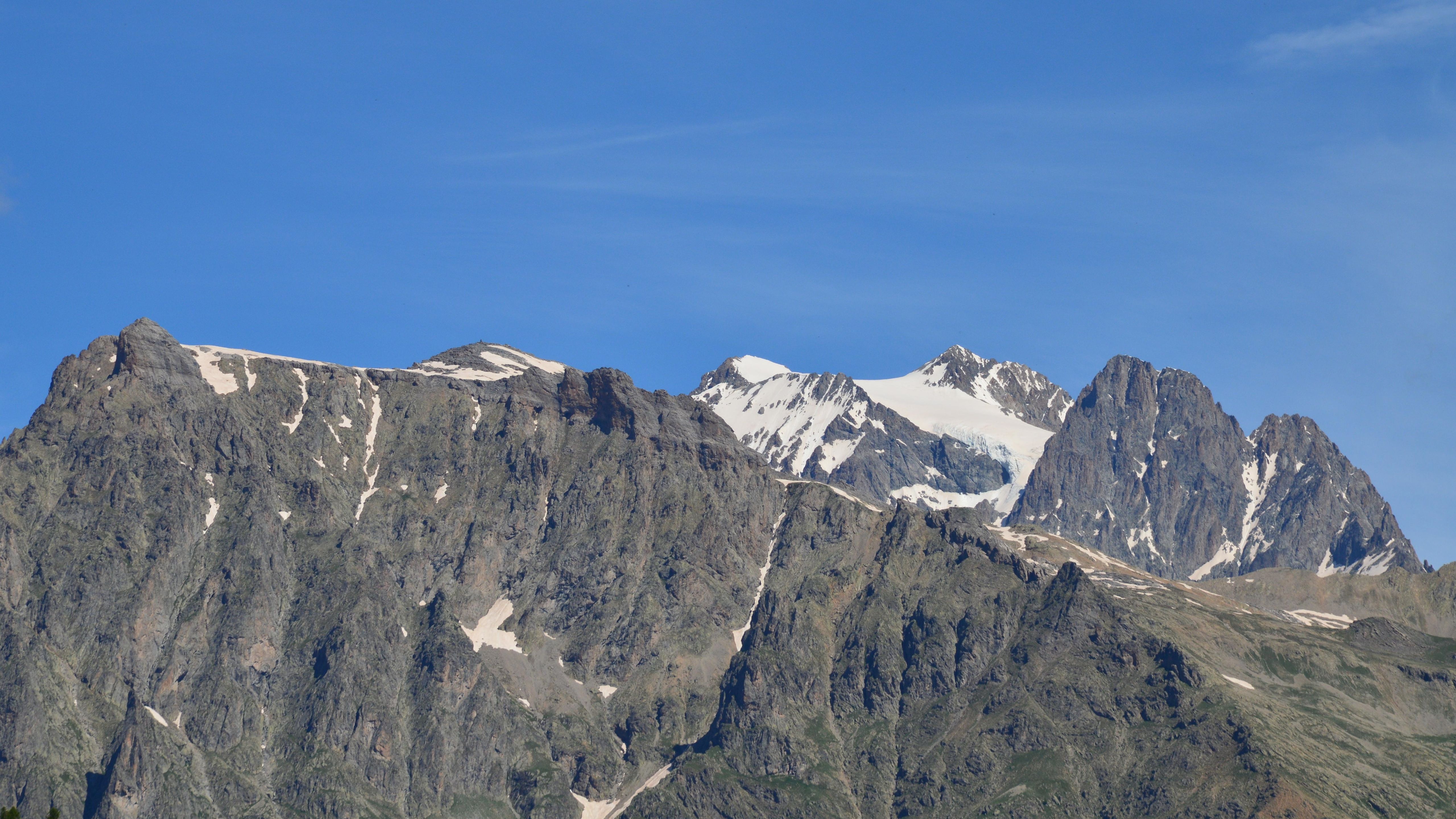A mountain range with snow capped peaks and a blue sky · Free Stock Photo
