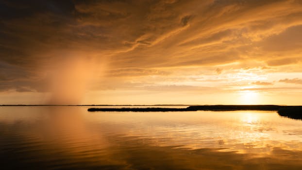 Stunning sunset over a calm lake in Svencelė, Lithuania, with vibrant orange sky and reflections.