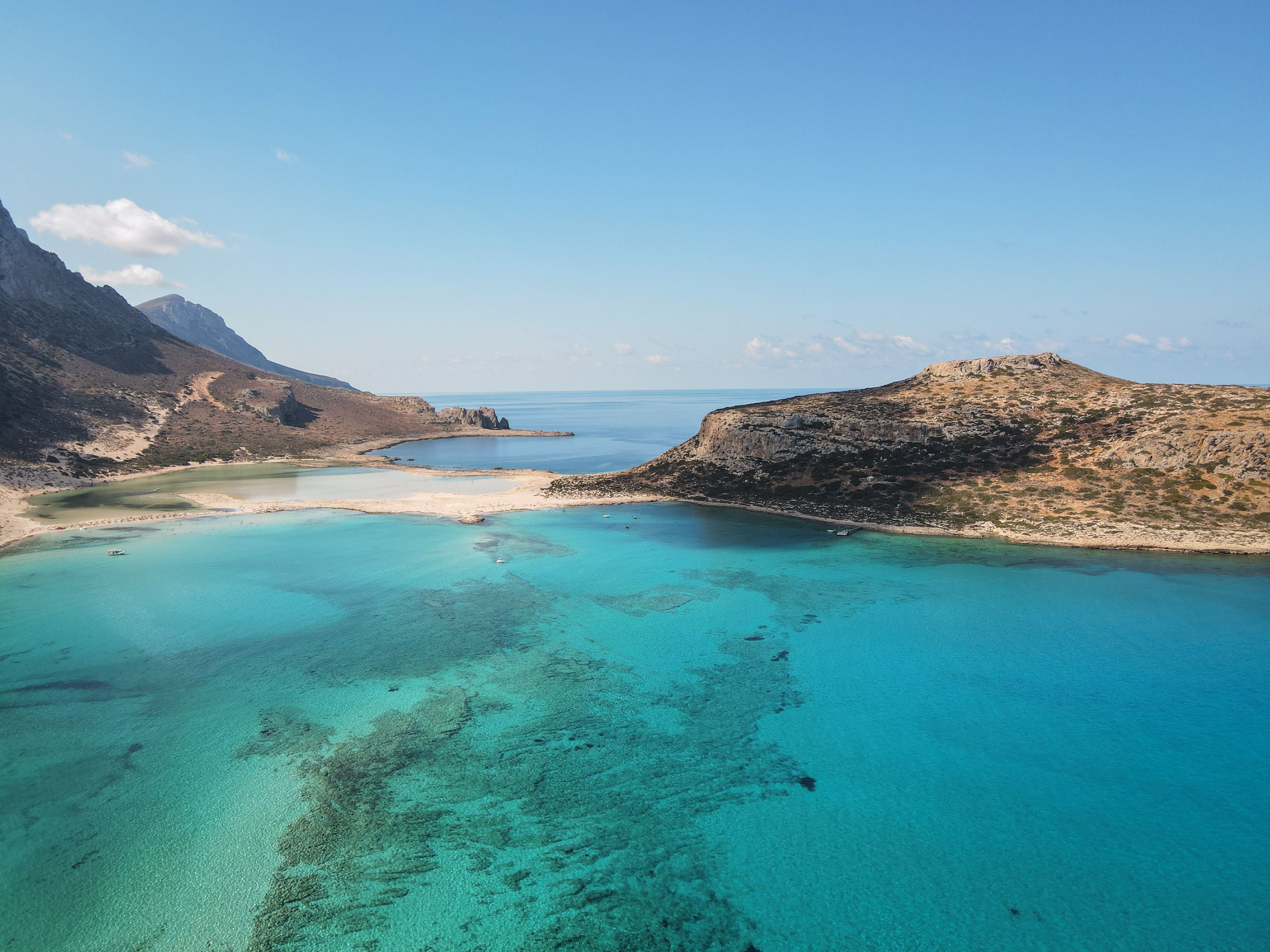 Breathtaking aerial capture of a turquoise lagoon and rugged island coastline under clear blue skies. - Photo by Francesco Ungaro on Pexels