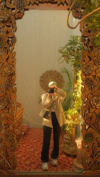 Stylish woman in mirror capturing photo in a decorative interior setting.