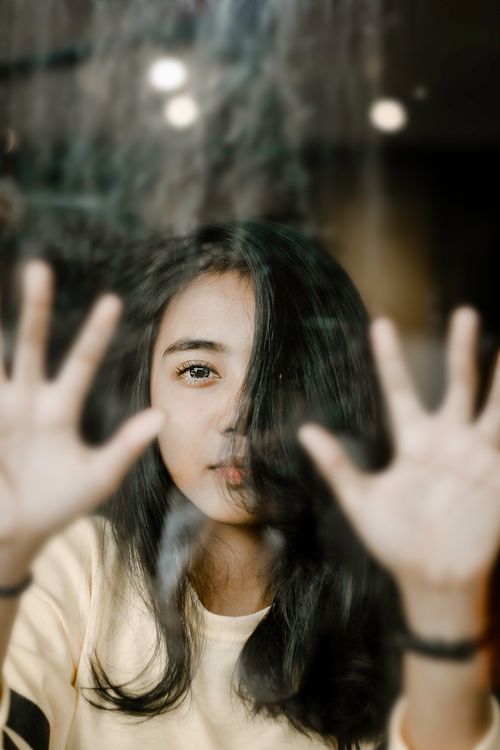 Free Artistic portrait of a young woman pressed against glass, conveying emotion and introspection. Stock Photo