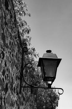 Artistic black and white photo of a vintage lantern mounted on a stone wall in Santiago de Querétaro, Mexico.
