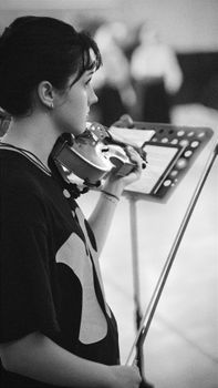 A focused black and white portrait of a woman playing the violin during a performance.