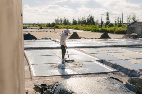 Free A solitary worker using a rake to harvest salt in a rural outdoor field. Stock Photo