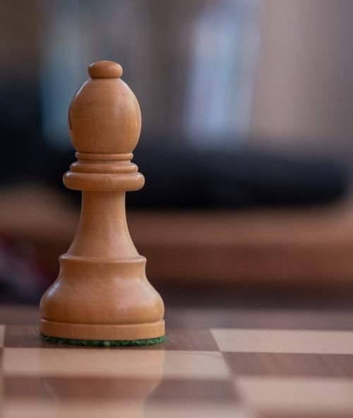 Free A detailed view of a chess pawn on a wooden board, highlighting strategy and contemplation. Stock Photo