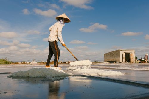 Free A farmer in a conical hat collects salt in a bright rural landscape. Stock Photo