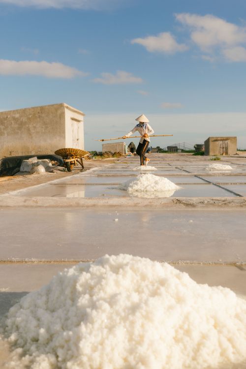Free A worker in Vietnam harvesting salt at a rural salt flat under the sunlight. Stock Photo