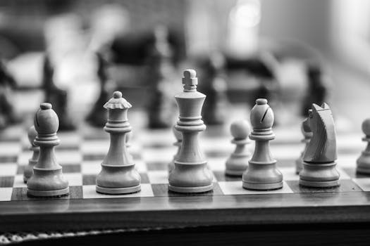 Black and white close-up of wooden chess pieces on a chessboard, emphasizing strategy and gameplay.