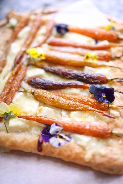 Free Close-up of a savory carrot tart adorned with vibrant edible flowers. Stock Photo