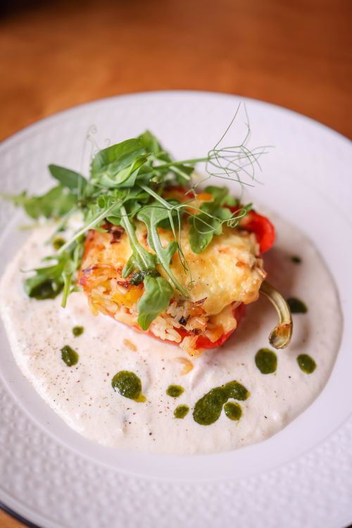 Free Delectable stuffed bell pepper topped with greens, served on a creamy sauce. Stock Photo