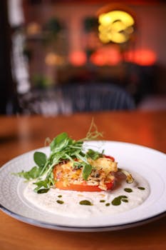 Delicious gourmet stuffed pepper with fresh greens, elegantly plated in a restaurant setting.