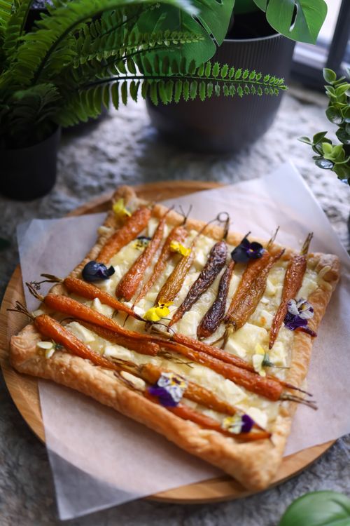 Free Rustic puff pastry tart featuring glazed carrots and edible flowers, perfect for a gourmet meal. Stock Photo