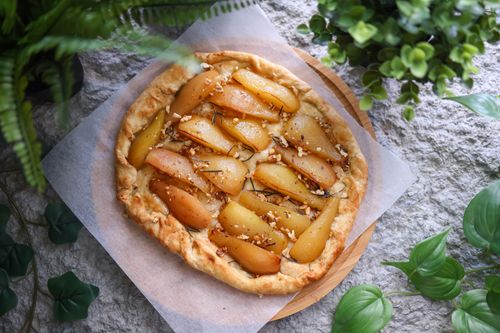 Free Homemade pear tart with nuts and herbs on a rustic stone background surrounded by greenery. Stock Photo