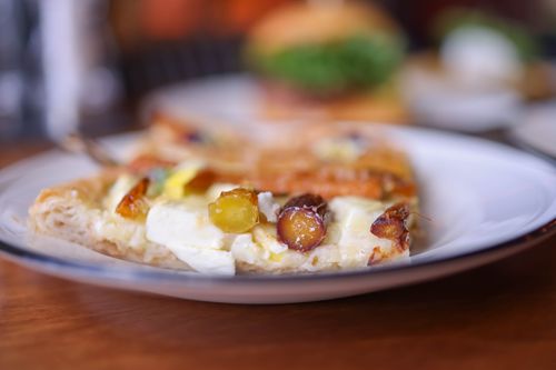 Free Close-up of a gourmet cheese and fruit pizza slice, elegantly presented. Stock Photo