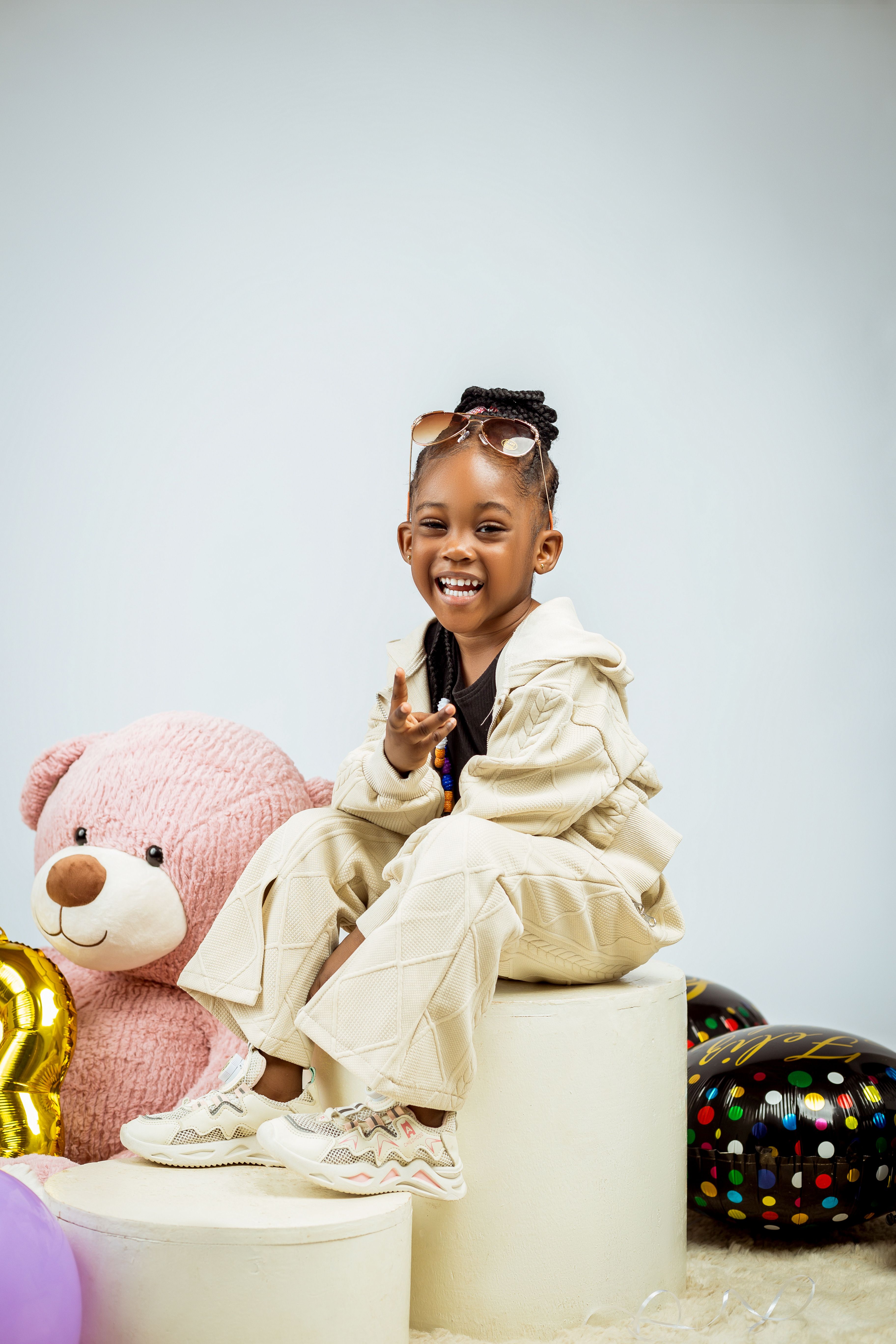 Happy child poses with a pink teddy bear in an indoor studio setting, exuding joy and playfulness.