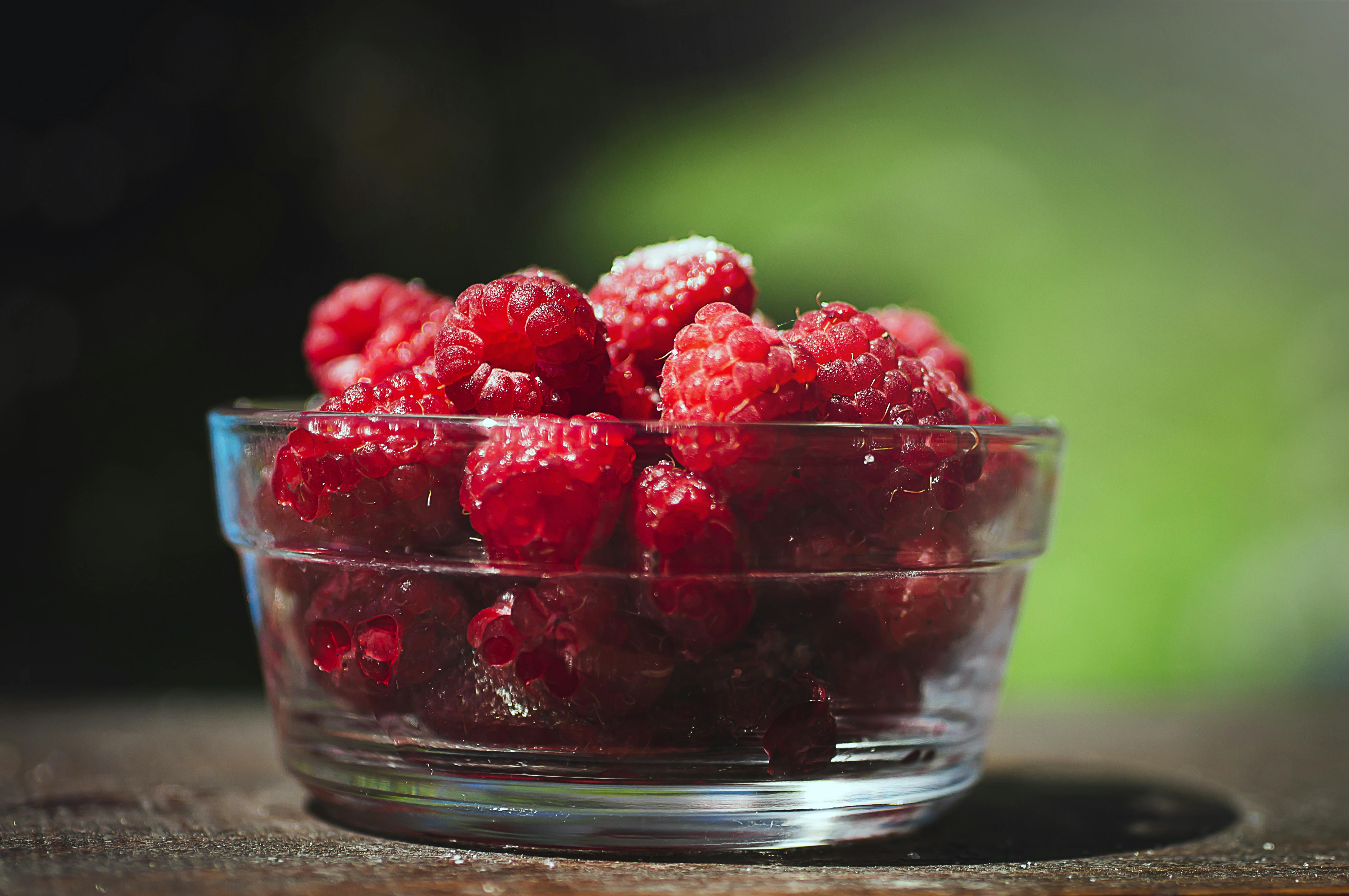 A bowl of raspberries on a table