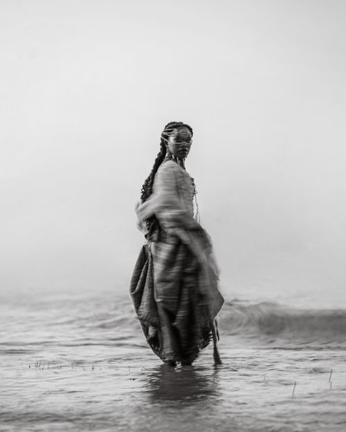 Free Black and white artistic portrait of a woman standing in shallow water. Stock Photo