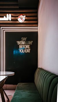 Modern restaurant interior featuring a neon sign and seating area, creating a cozy atmosphere.