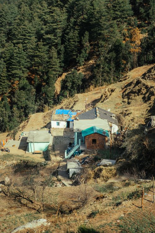 Free Scenic aerial view of remote village houses nestled in a forested mountainside. Stock Photo