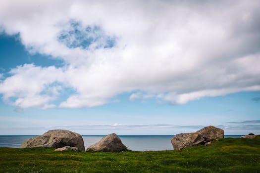 Idyllic view of lush green grass, rocky shore, and blue sky at Eggum, Norway.