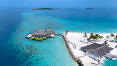Free Stunning aerial photo of a tropical beach resort in Maldives surrounded by turquoise waters and white sandy beaches. Stock Photo
