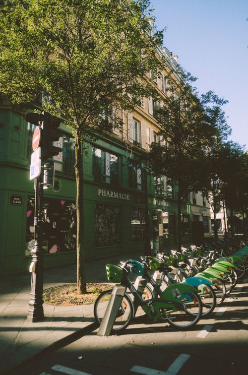 Free Row of bicycles for rent by a shaded building on a sunny city street. Stock Photo