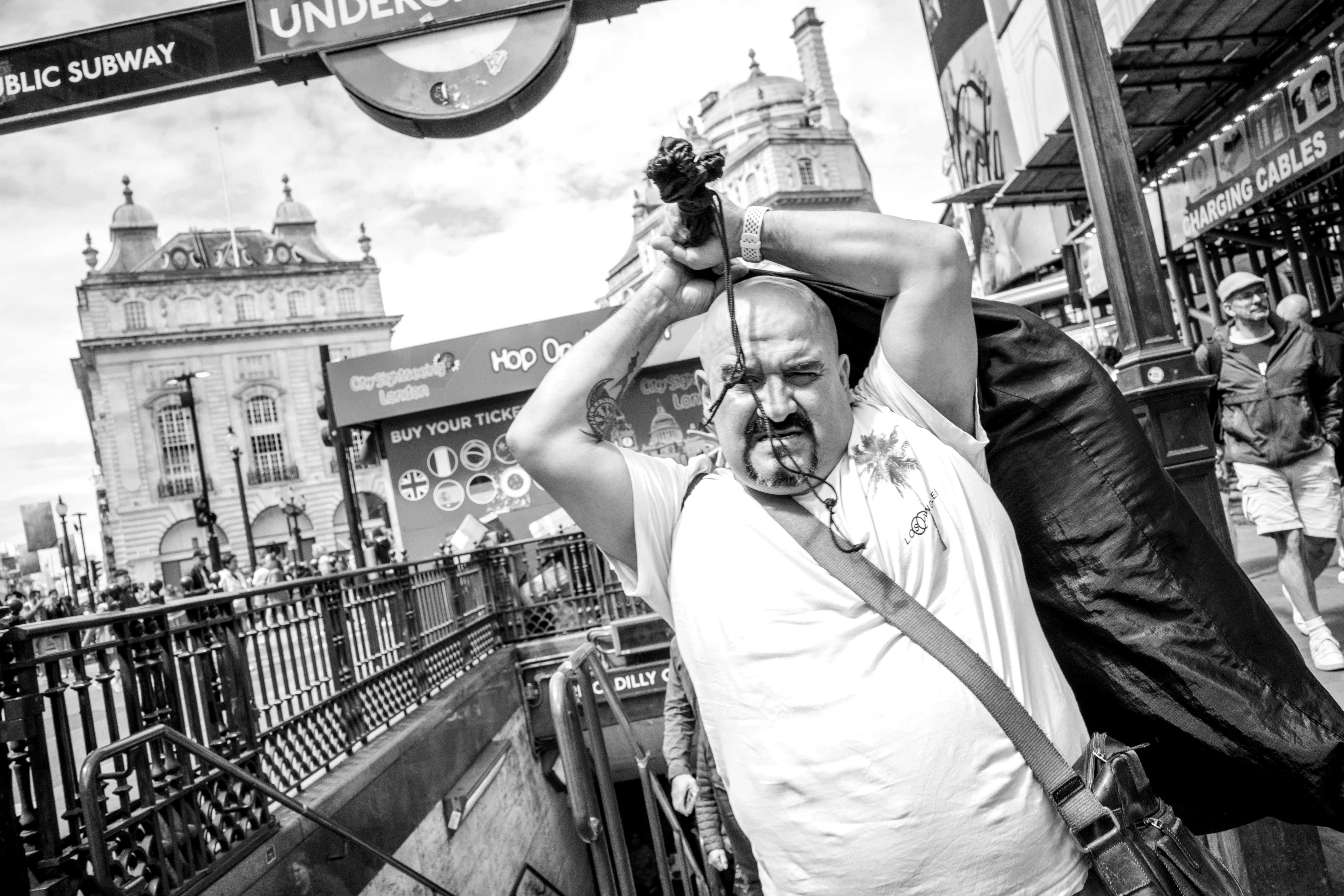 A man carrying a sack at a bustling London underground entrance, capturing urban life.
