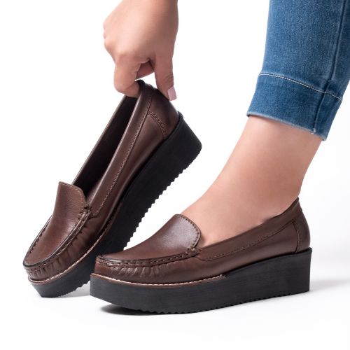 Free Stylish brown platform loafers being worn and held, set against a white studio backdrop. Stock Photo