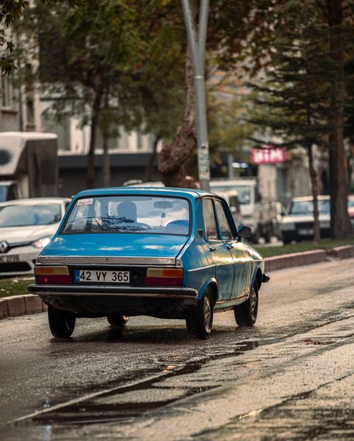 Free Retro blue car on a wet city street, showcasing vintage urban transportation. Stock Photo