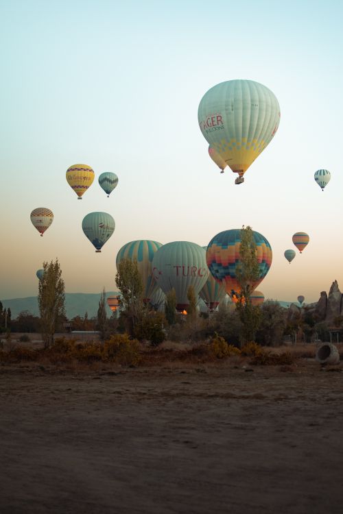 Free Hot air balloons floating over a picturesque landscape during sunrise, capturing adventure and tranquility. Stock Photo