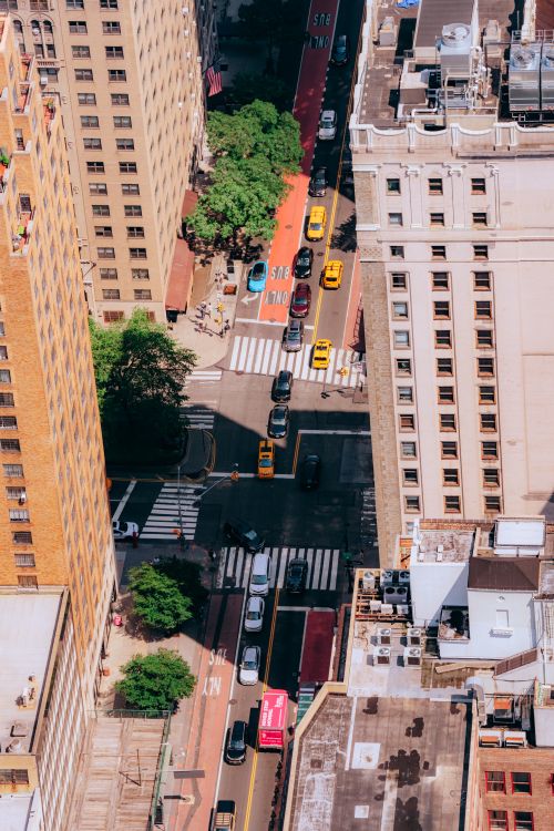 Free Bird's eye view of a busy New York City street intersection with traffic and towering buildings. Stock Photo