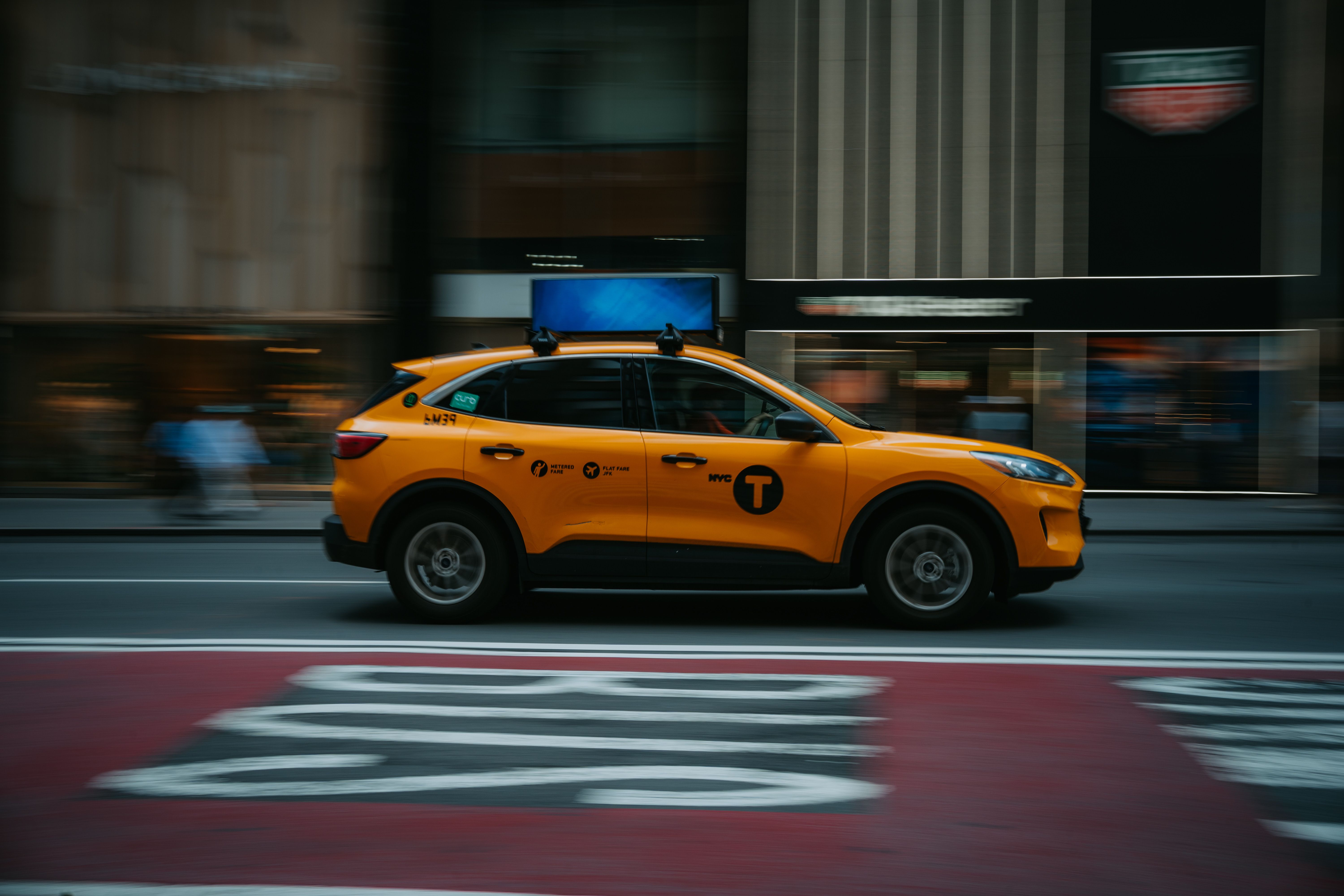 A yellow NYC taxi speeds through the bustling city streets, capturing urban life in motion.