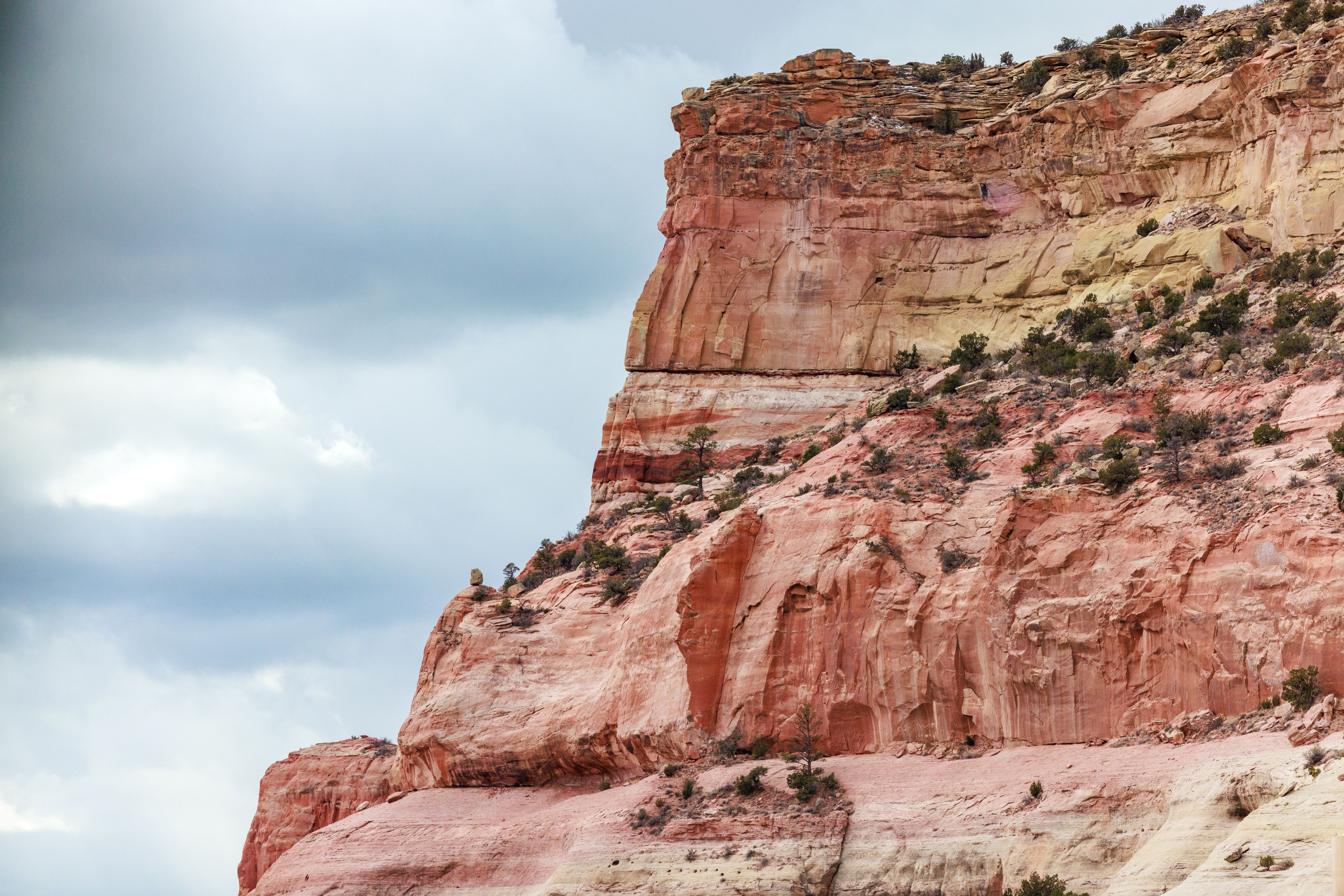 Breathtaking view of a red rock cliff formation showcasing natural beauty against a cloudy sky. Perfect for nature lovers.