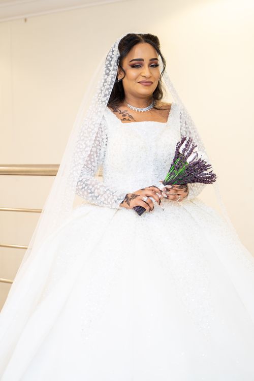 Free Beautiful bride in white wedding dress with lavender bouquet indoors, showcasing elegance and joy. Stock Photo