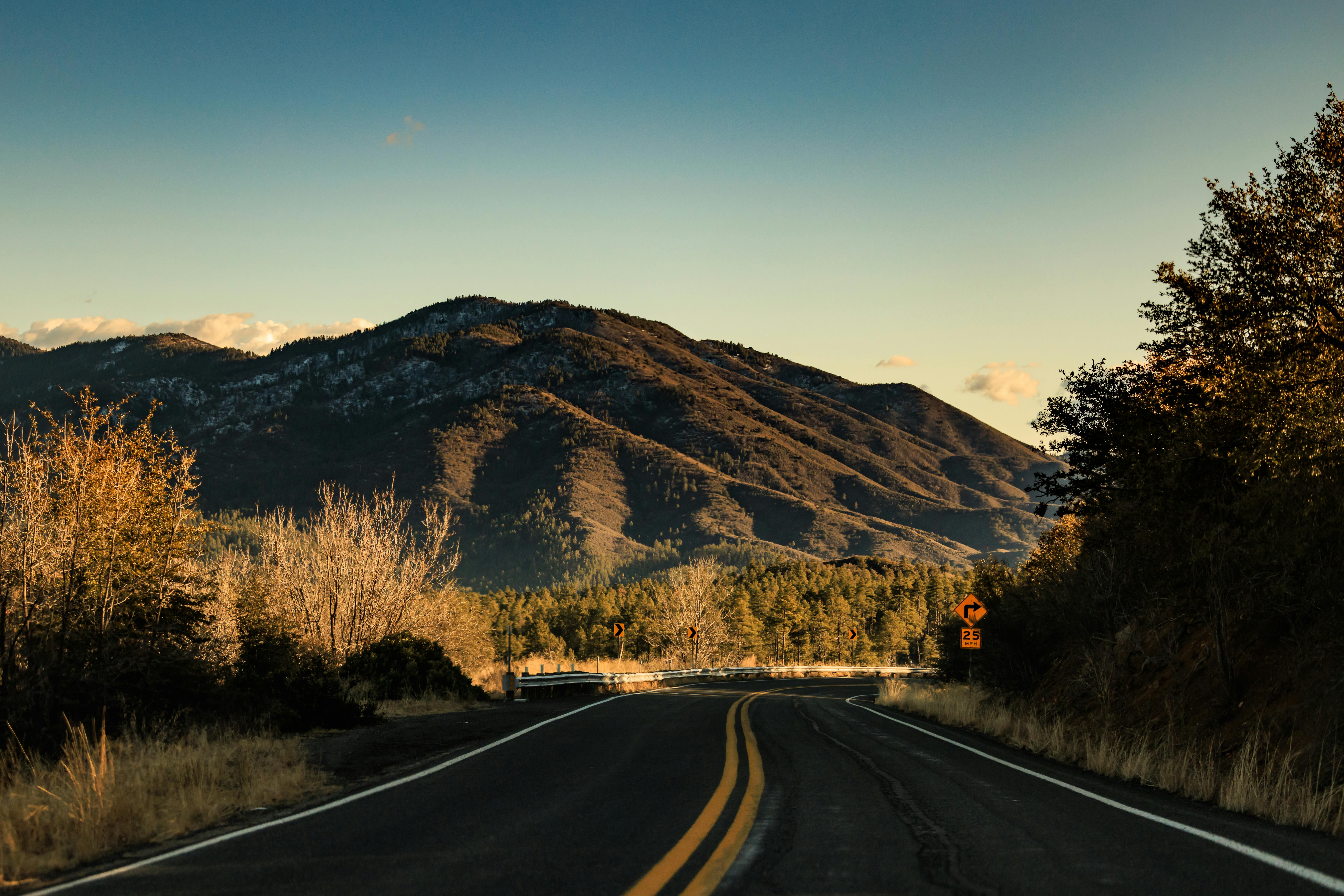 Captivating view of a winding road leading to mountain under a dramatic sunset sky.