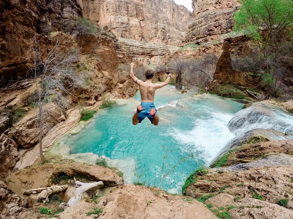 Topless Man Jumping on Body of Water