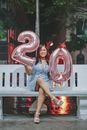 Photo of Woman Sitting While Holding  20 Balloons Signage