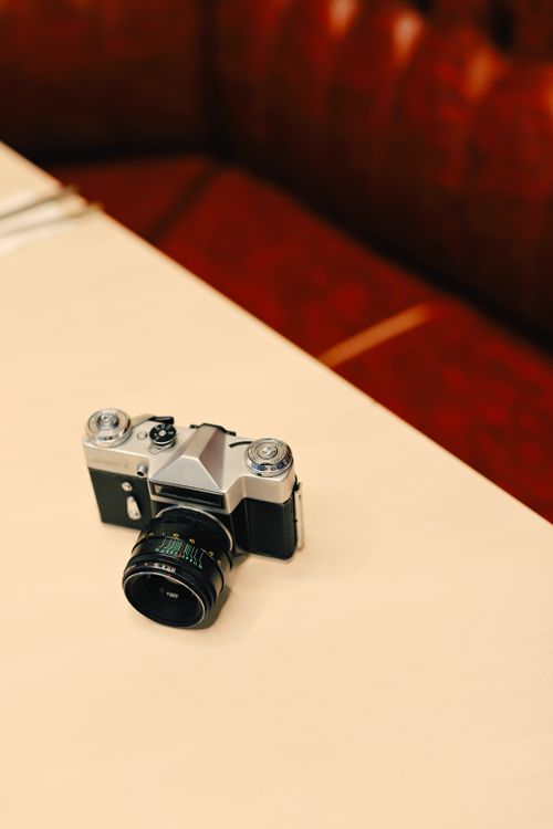 Free A classic vintage film camera resting on a light wooden table with a retro background. Stock Photo